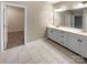 Bright bathroom with double sinks, tile flooring, and a doorway leading to a walk-in closet at 8212 Merryvale Ln, Charlotte, NC 28214