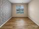 Bright bedroom with geometric wallpaper, wood-look floors and window view at 8212 Merryvale Ln, Charlotte, NC 28214