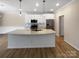 Modern kitchen featuring an island, stainless steel appliances, white cabinets, and wood-look floors at 8212 Merryvale Ln, Charlotte, NC 28214
