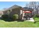 Charming brick home exterior featuring a patio with a red umbrella, lush lawn, and mature landscaping at 13008 Ginovanni Way, Mint Hill, NC 28227