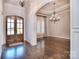 Elegant foyer with dark hardwood floors, grand chandelier, and beautiful archway to living spaces at 13008 Ginovanni Way, Mint Hill, NC 28227