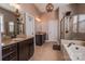 Well-lit bathroom with a double vanity, granite counters, a glass-enclosed shower, and a relaxing soaking tub at 15125 Skypark Dr, Huntersville, NC 28078