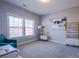 Bright bedroom featuring a window, accent chair, shelving and soft carpeting; a functional and comfortable space at 15125 Skypark Dr, Huntersville, NC 28078