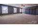 Expansive bonus room with a carpeted floor, a ceiling fan, and windows offering natural light; shelving at the far end at 15125 Skypark Dr, Huntersville, NC 28078