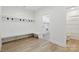 Bright mudroom features custom bench with coat hooks, wood flooring, and adjacent laundry and bathroom spaces at 160 Belfry Loop, Mooresville, NC 28117