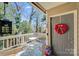 Cozy front porch with a welcoming wreath, seating, and a view of the surrounding greenery at 1606 Sharon W Rd, Charlotte, NC 28210