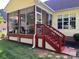 The enclosed sunroom with red stairs, hanging plants and outdoor seating at 1674 Wakefield Way, Rock Hill, SC 29730