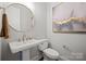 Stylish powder room with pedestal sink, round mirror, and elegant gold fixtures at 180 Twin Sisters Ln, Mooresville, NC 28117