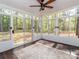 Sunroom with glass windows offering peaceful views, ceiling fan, and dark stained wood flooring at 207 Windsor Greene Dr, Monroe, NC 28110