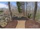 A serene backyard retreat with a stone fire pit and lush landscaping, offering a peaceful outdoor space at 3196 Stonemill Path, Sherrills Ford, NC 28673