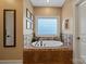 A large soaking tub below a picture window is surrounded by decorative tile in this well-appointed bathroom at 3196 Stonemill Path, Sherrills Ford, NC 28673