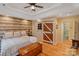 Inviting bedroom with wood paneling, tray ceiling, and a rustic sliding barn door to the bathroom at 3196 Stonemill Path, Sherrills Ford, NC 28673