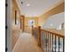 A carpeted hallway with wrought iron railing and overhead chandelier draws the eye to the back of the house at 3196 Stonemill Path, Sherrills Ford, NC 28673