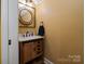 Charming powder room featuring a rustic vanity, round mirror and warm, inviting wall color at 3196 Stonemill Path, Sherrills Ford, NC 28673
