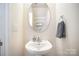Cozy half bath features a pedestal sink, oval mirror, and neutral paint at 7361 Sun Dance Dr, Fort Mill, SC 29707