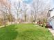 Expansive backyard with lush green lawn, mature trees, wooden deck and playground area at 7801 Snowden Ln, Charlotte, NC 28270