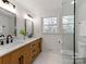 Bright bathroom featuring a double vanity, marble countertops, black hardware and a glass-enclosed shower at 7801 Snowden Ln, Charlotte, NC 28270