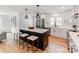 Modern white kitchen featuring a black island with bar stool seating and stainless steel appliances at 7801 Snowden Ln, Charlotte, NC 28270