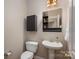 Cozy powder room featuring pedestal sink, cabinet storage, and decorative mirror shelving at 7806 Spanish Oaks Dr, Waxhaw, NC 28173