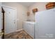 Efficient laundry room with washer, dryer, and shelving for storage, adjacent to an exterior door at 7806 Spanish Oaks Dr, Waxhaw, NC 28173