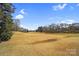 Expansive green field with scattered trees and a glimpse of surrounding homes at 8501 Golf Ridge Dr, Charlotte, NC 28277