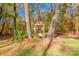 A charming wooden swing nestled between mature trees with lush foliage and a neatly manicured lawn at 10032 Hunters Trace Dr, Concord, NC 28027