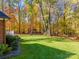 Manicured backyard with a large lawn, mature trees, and lush landscaping creates a serene outdoor oasis at 10032 Hunters Trace Dr, Concord, NC 28027