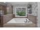This soaking tub features a window with a wooded view and black hardware at 10032 Hunters Trace Dr, Concord, NC 28027