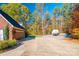Long driveway leading to a brick house with a two-car garage, set amid lush landscaping and mature trees at 10032 Hunters Trace Dr, Concord, NC 28027