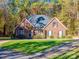 Charming brick home with a manicured lawn and beautiful fall foliage in the background at 10032 Hunters Trace Dr, Concord, NC 28027