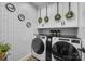 Laundry room with modern appliances, patterned wallpaper, and white cabinets with decorative wreaths at 10032 Hunters Trace Dr, Concord, NC 28027