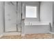 Bathroom featuring a modern bathtub and a glass-enclosed shower, with natural light from a window at 11203 Chapeclane Rd, Charlotte, NC 28278