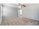 Large, carpeted bedroom with a ceiling fan and natural light, with an open doorway at 11203 Chapeclane Rd, Charlotte, NC 28278