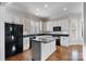 An open kitchen with black appliances, white cabinets, and hardwood floors at 1131 S Kings Dr, Charlotte, NC 28207