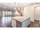 Open concept kitchen with granite island, adjacent to living room with dark floors and staircase at 11679 Red Rust Ln, Charlotte, NC 28277