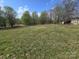 Overgrown backyard with established lawn, mature trees, and a shed, perfect for outdoor storage and utility at 117 Jones Rd, Shelby, NC 28150