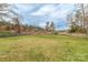 A large grassy yard, with mature trees and a wire fence, is ready for outdoor recreation at 1216 Center St, Wadesboro, NC 28170