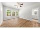 A sun-filled bedroom with ceiling fan, wood-look floors, and a door to a bathroom at 1322 Condon St, Charlotte, NC 28216