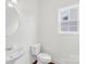 Bright half bathroom features a sink with a round mirror and a toilet at 13514 Porter Creek Rd, Charlotte, NC 28262