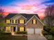 Beautiful sunset view of a brick two-story home, featuring a two-car garage at 13514 Porter Creek Rd, Charlotte, NC 28262