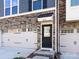Close-up of townhome exterior with stone accents, front door, and two-car garage at 1814 Shumard Ln, Charlotte, NC 28205