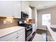 Well-lit kitchen featuring stainless steel appliances, stylish backsplash, and white cabinetry at 1814 Shumard Ln, Charlotte, NC 28205