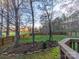 Landscaped backyard with a wooden fence, mature trees, and a view of the lush lawn at 3229 Leicester Dr, Matthews, NC 28104