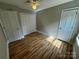 Light-filled bedroom has wood-look flooring, fan, and large double-door closet in neutral color scheme at 3424 Red Fox Trl, Matthews, NC 28104