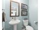 Stylish powder room with a pedestal sink, decorative mirror, and black-and-white botanical-themed artwork at 4102 Harmony Hills Dr, Matthews, NC 28104
