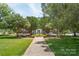 Scenic park view with lush trees, green grass, a paved walkway, and a charming building in the distance at 4102 Harmony Hills Dr, Matthews, NC 28104