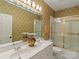 Well-lit bathroom with double sinks, patterned wallpaper, and a shower with gold trim at 4510 Old Course Dr, Charlotte, NC 28277