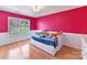 bedroom featuring a bright pink accent wall, hardwood floors, and built in drawers at 4634 Craigmoss Ln, Charlotte, NC 28278