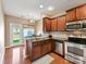 Cozy kitchen featuring stainless appliances, wood cabinets, and view to breakfast area at 4634 Craigmoss Ln, Charlotte, NC 28278