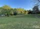 Expansive grassy backyard with mature trees on a sunny day at 4790 Polk Ford Rd, Stanfield, NC 28163